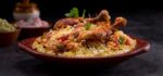 Chicken biriyani using jeera rice arranged in an earthenware with raitha on grey background _ Premium Photo