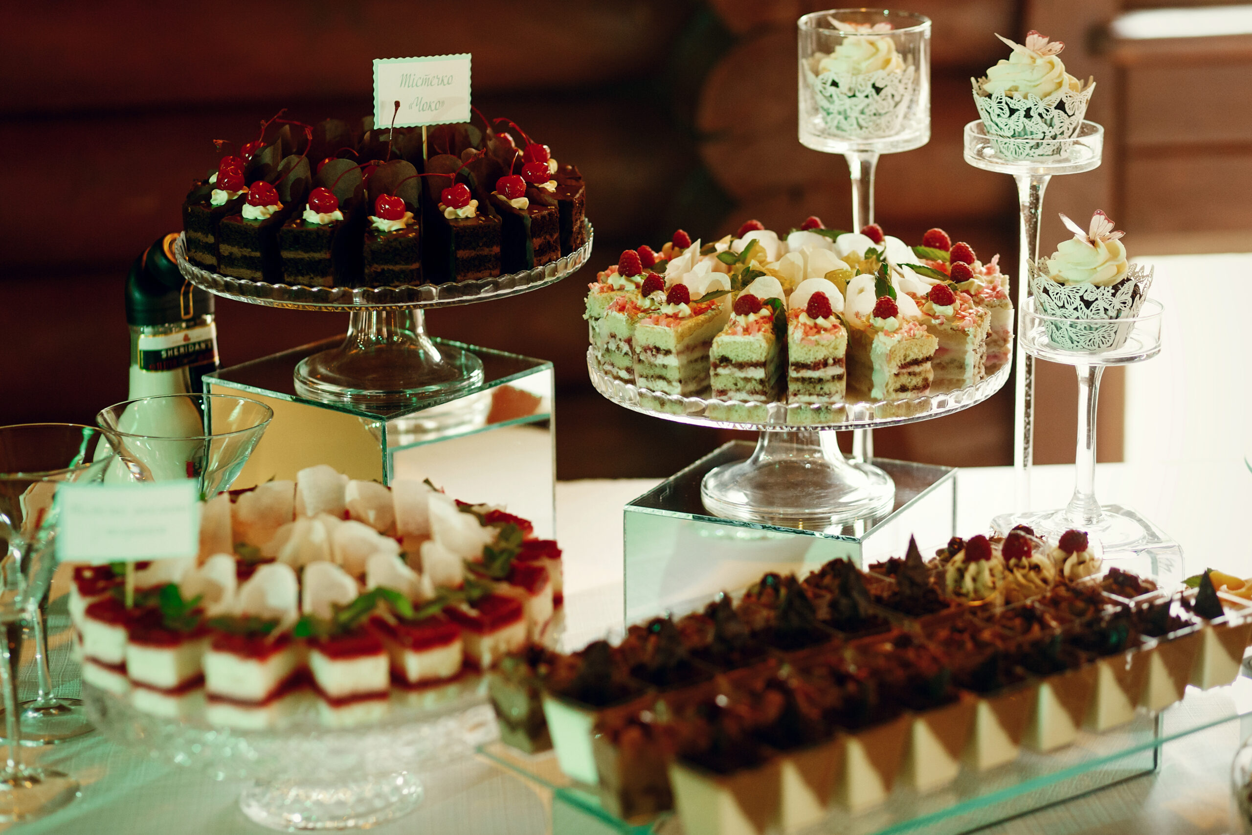 Tasty fruit and chocolate cakes stand on glass plates Tasty fruit and chocolate cakes stand on glass plates
